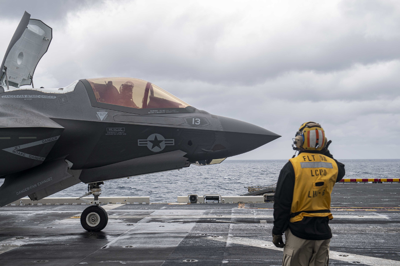 A Sailor looking at a fighter jet on an aircraft carrier